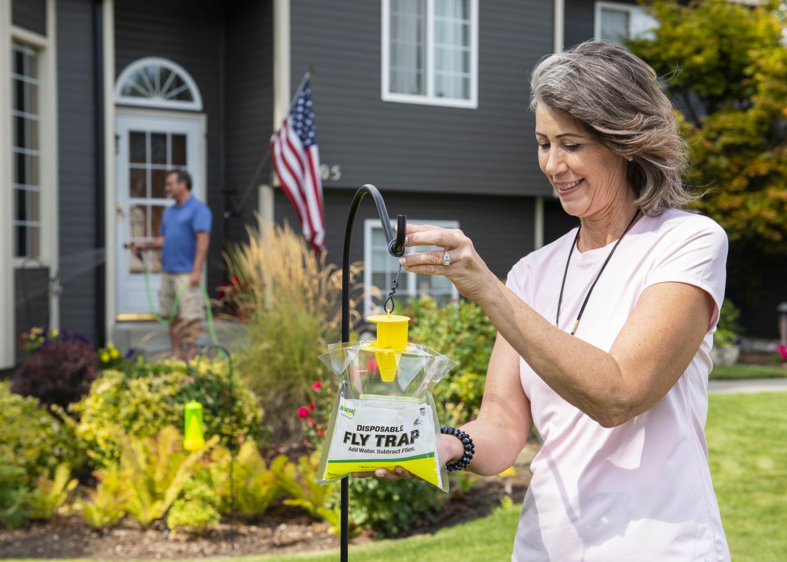 Woman hanging RESCUE! Disposable Fly Trap in front yard