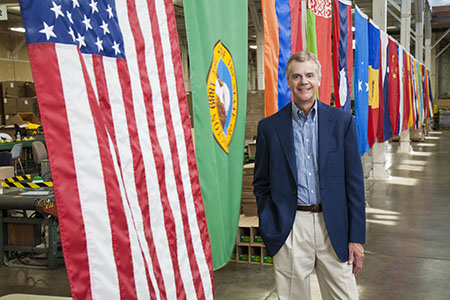 Rod Schneidmiller, founder and president of RESCUE! Pest Control Products, stands with the American flag, the Washington state flag, and other flags representative of our employees' nationalities. 